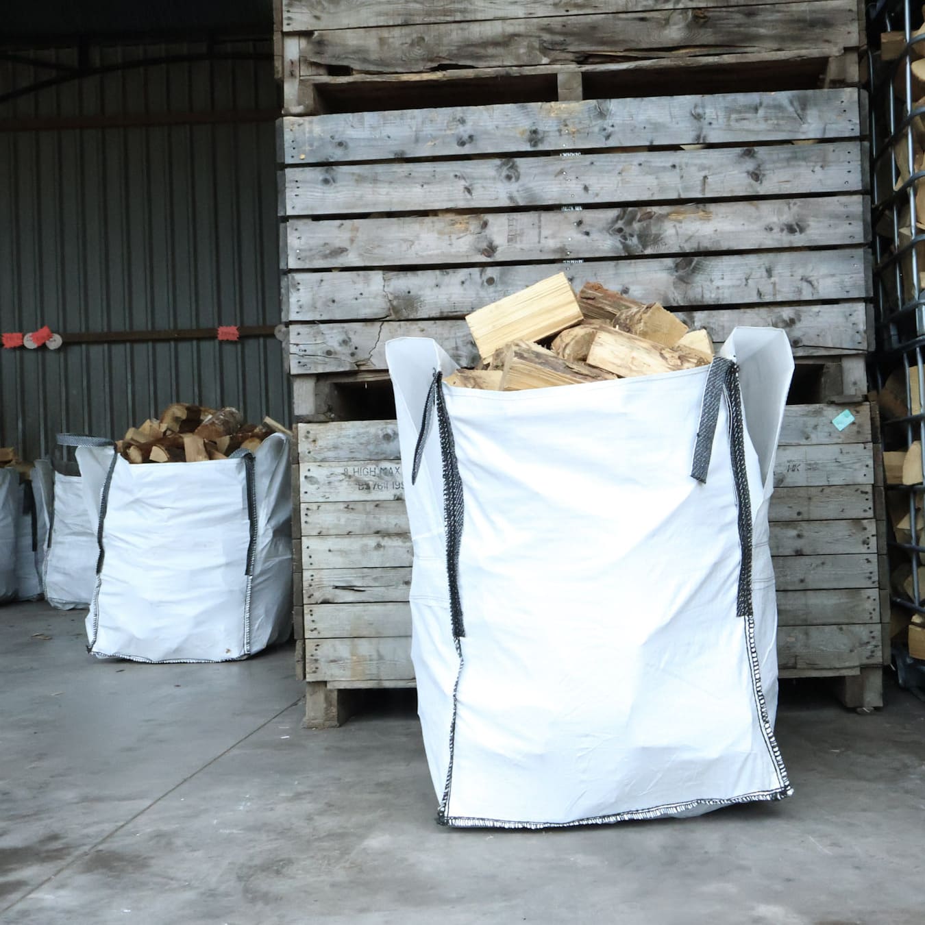 White bags filled with wood next to wooden pallets in a storage area