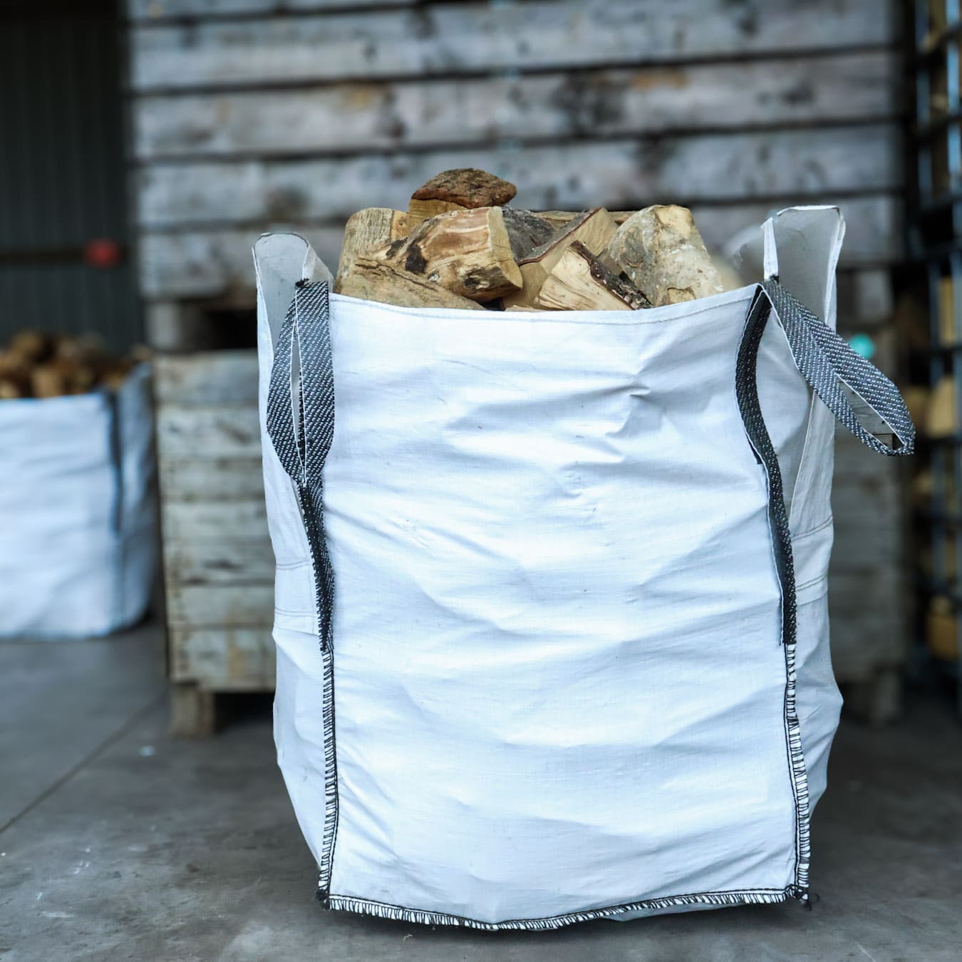 White bulk bag filled with wooden logs in an industrial setting