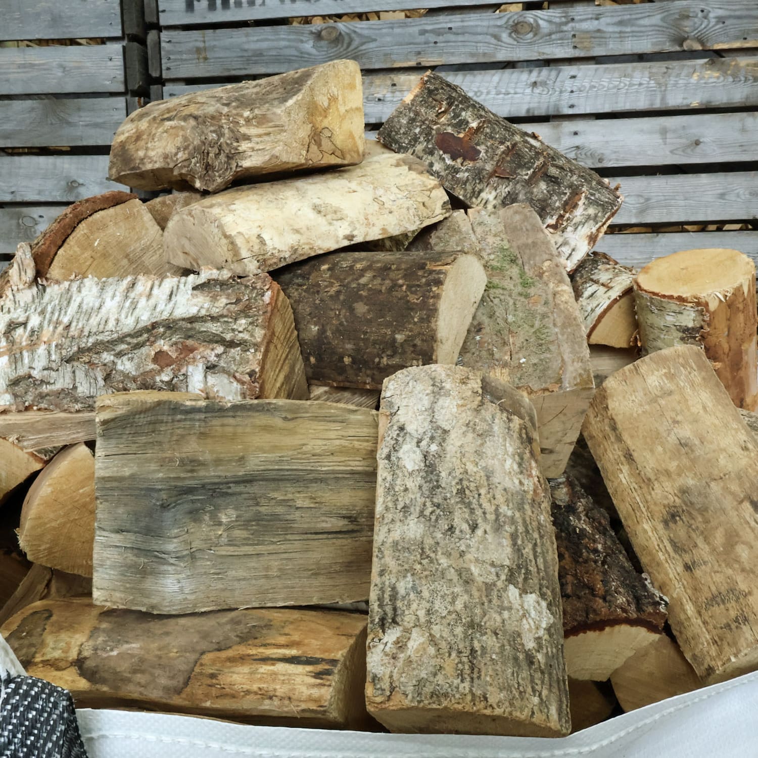 Stack of seasoned hardwood firewood logs against a wooden background. also known as barn dried logs