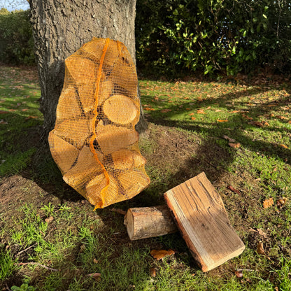 Netted kiln dried oak logs under oak tree