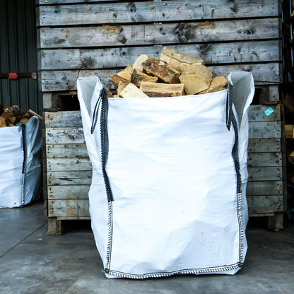 White bulk bag filled with firewood against a wooden pallet background