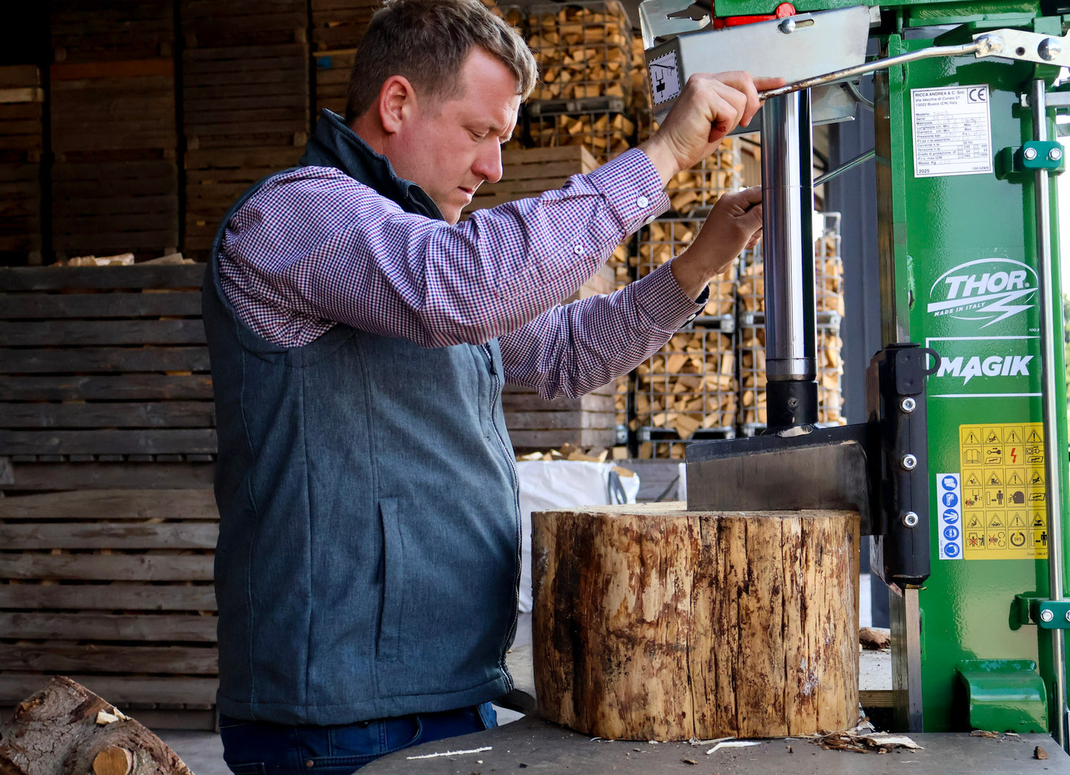 Man operating a green Thor Magik wood processing machine with a log in front of him.