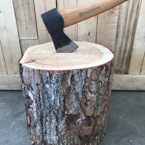 A chopping block with an axe embedded in it, showing the wood grain and a portion of the axe handle.